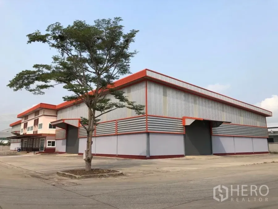 工厂 出租在Bang Len, Nakhon Pathom - 邦伦区现代钢结构工厂，红色装饰，宽阔混凝土车道与装卸区。