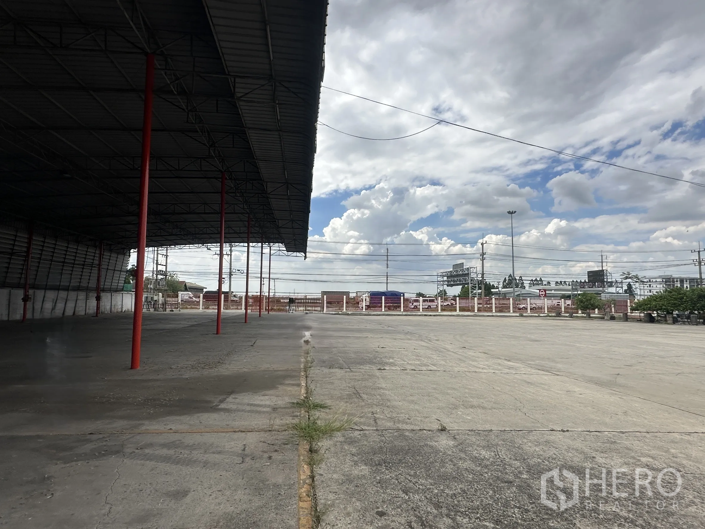 Land for rent in Wang Noi, Phra Nakhon Si Ayutthaya - Covered loading shed beside a large concrete apron and roadside fencing.