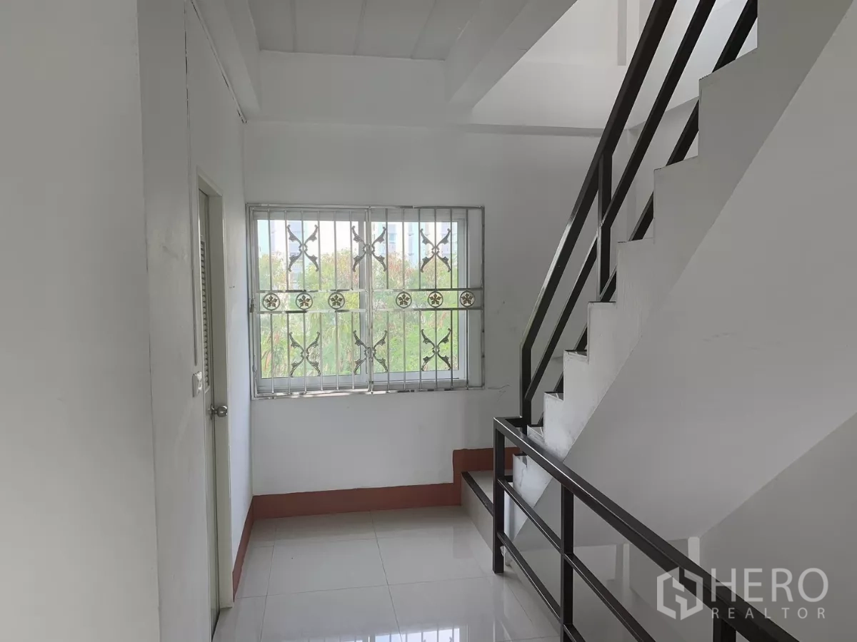 Home Office for rent in Lat Krabang, Bangkok - Stair landing with metal handrail, grilled window and door to a restroom or storage.