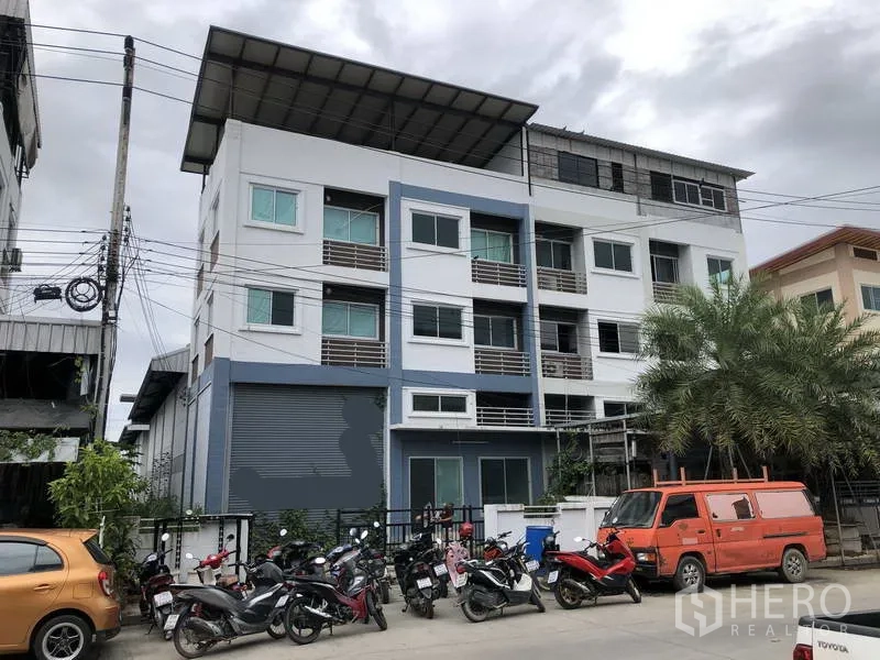 Warehouse for rent in Lat Lum Kaeo, Pathum Thani - Street view of a multi-storey warehouse and office building with a roller shutter and front parking.