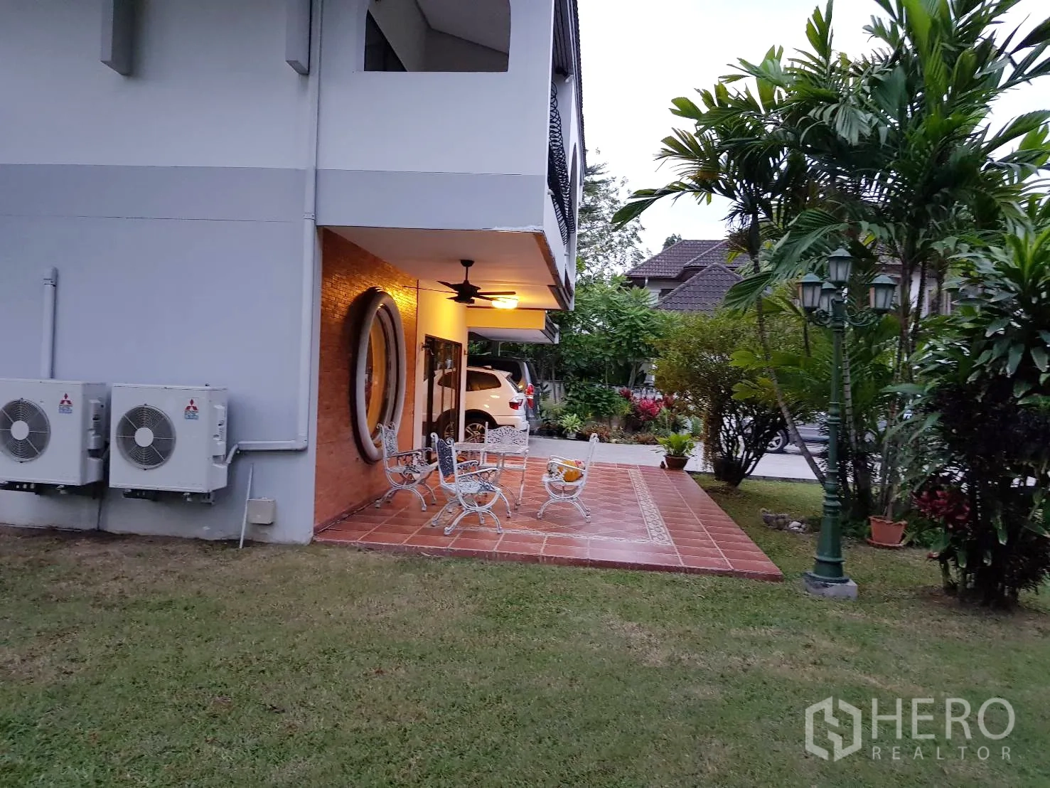 บ้าน ให้เช่าในKhan Na Yao, Bangkok - ชานปูกระเบื้องพร้อมชุดโต๊ะเก้าอี้ ใต้กันสาดติดพัดลม รายล้อมด้วยสวนสวยใกล้ทางรถเข้า