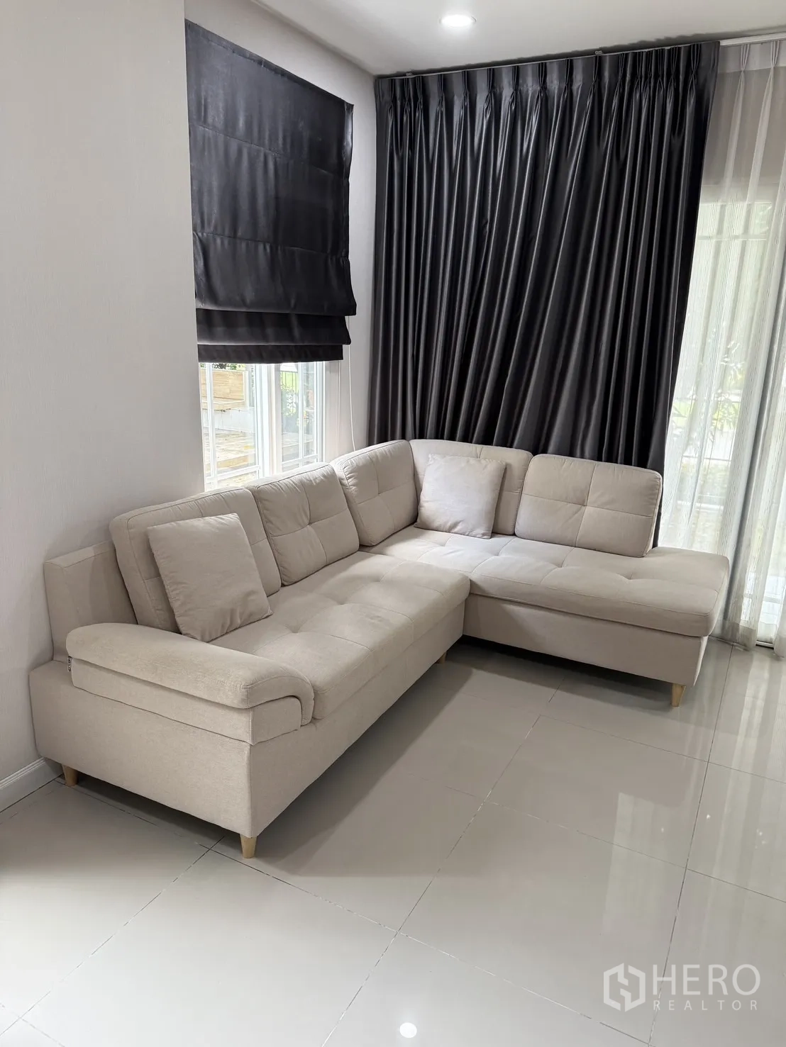 บ้าน ให้เช่าในBang Kapi, Bangkok - ห้องนั่งเล่นอบอุ่น โซฟาแอลสีเบจ พร้อมผ้าม่านสูงจรดเพดาน