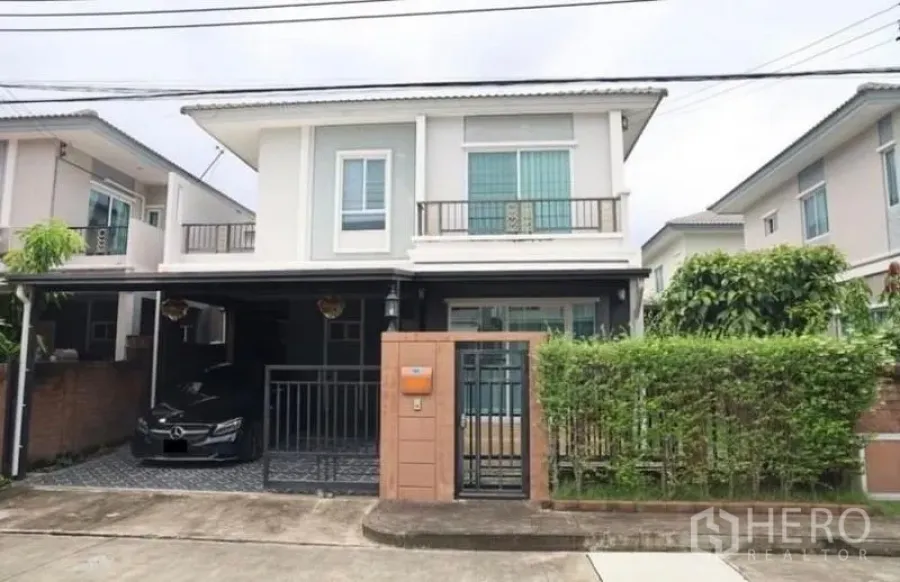 Detached House for rent in Suan Luang, Bangkok - Front view of a modern two-storey detached house with gated entrance, covered carport and small hedge-lined garden.