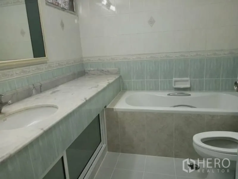 Condominium for rent in Watthana, Bangkok - Tiled bathroom featuring a bathtub, long marble countertop with sink, mirror and toilet.
