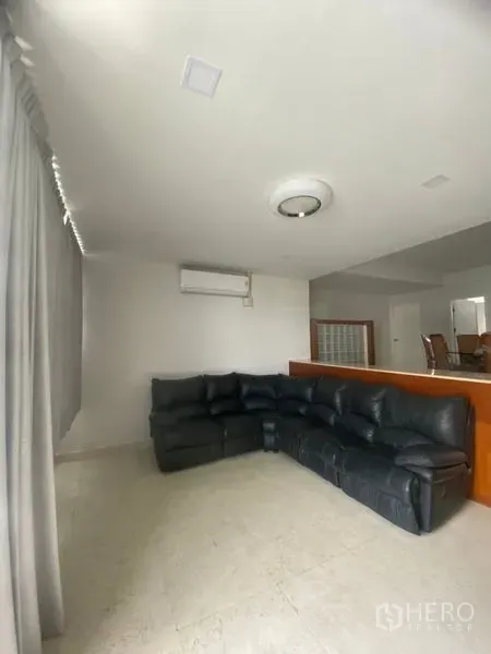 公寓 出租在Sathon, Bangkok - 明亮客厅，黑色真皮转角沙发，瓷砖地面，空调与落地窗帘。