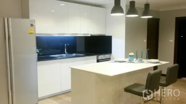 Condominium for rent or sale in Watthana, Bangkok - Bright modern kitchen with white cabinets, island and pendant lights.