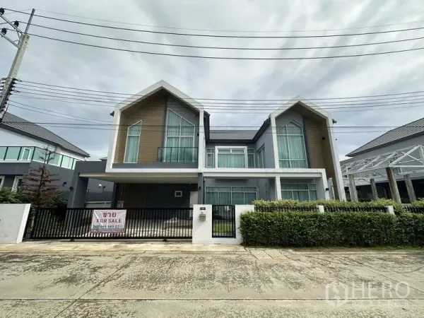 独立式住宅 出售在Lam Luk Ka, Pathum Thani - 现代两层独栋别墅，双坡屋顶，前方有围栏与出售标识。