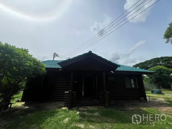 สำนักงานที่บ้าน ให้เช่าในSuan Luang, Bangkok - มุมด้านหน้าอาคารไม้พร้อมชายคากว้าง สนามหญ้าและเสาไฟเหนือศีรษะ