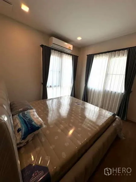 Detached House for rent in Samut Prakan - Cozy bedroom with AC, two windows and dark curtains.