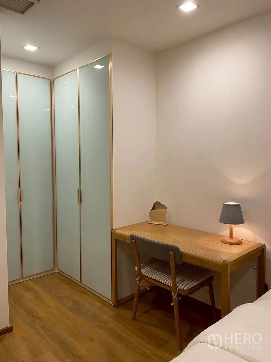 Condominium for rent in Watthana, Bangkok - Corner with frosted wardrobes and a wooden study desk with lamp.