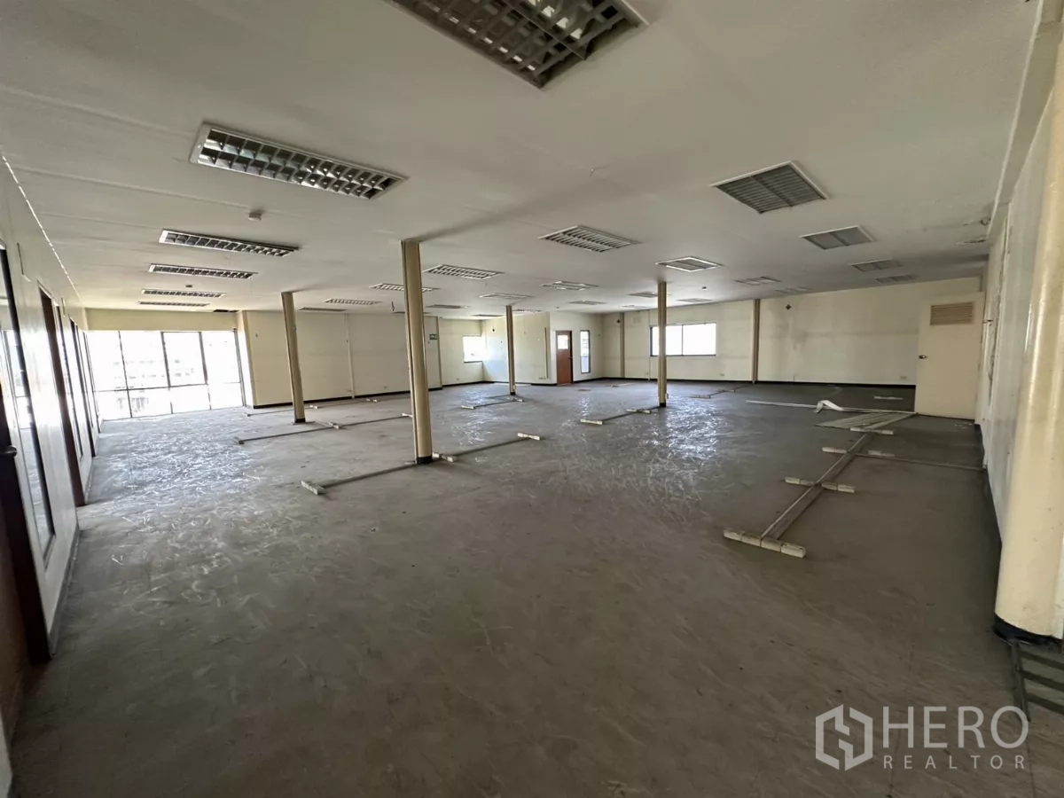 Warehouse for rent in Suan Luang, Bangkok - Large office workspace with pillars, floor cable ducts, and glass-fronted rooms.