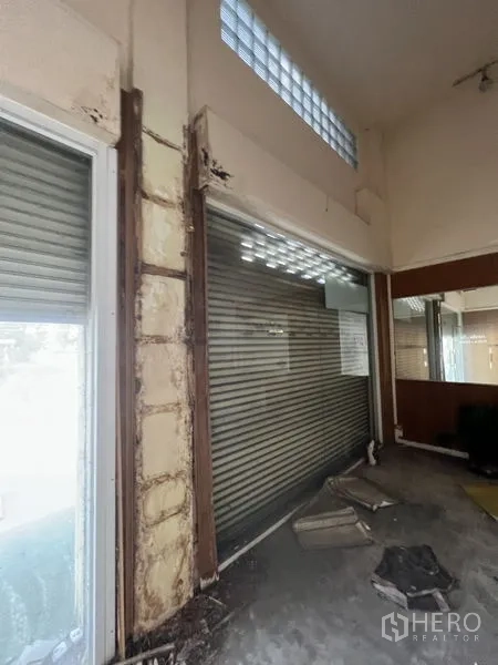 店屋 出租在Watthana, Bangkok - 室内视角可见卷帘门与展示窗，上方有玻璃砖采光。