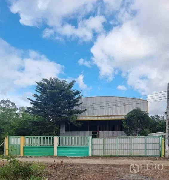 货栈 出租在Lat Krabang, Bangkok - Lat Krabang钢结构仓库外观，带滑动大门与绿树，天空晴朗