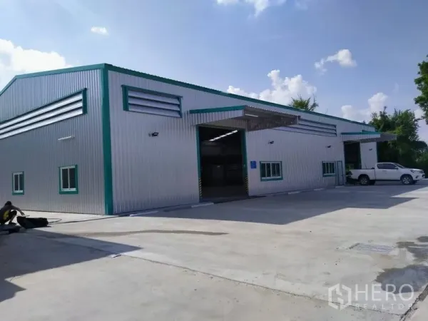 Warehouse for rent in Mueang Nonthaburi, Nonthaburi - Modern steel-clad warehouse exterior with wide concrete yard, loading bays and parking in Mueang Nonthaburi.