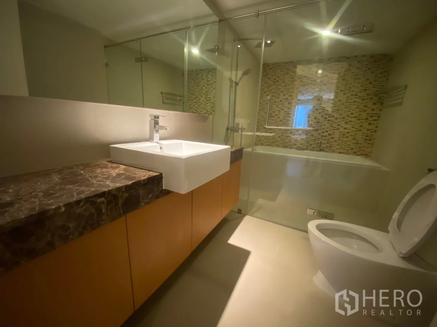 公寓 出租在Watthana, Bangkok - 卫浴带玻璃隔断浴缸、马赛克背景墙、方形台盆与大理石台面。