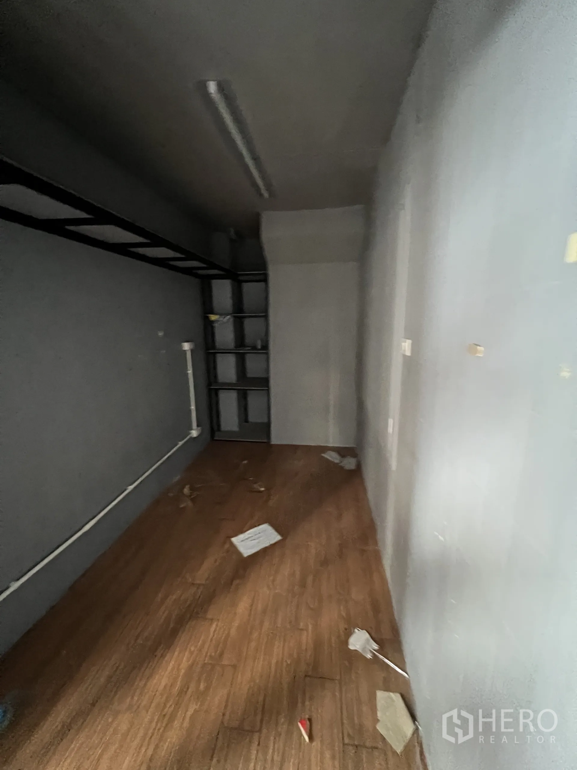 พื้นที่ขายปลีก ให้เช่าในPhaya Thai, Bangkok - ห้องเก็บของด้านหลัง ผนังสีเข้ม พื้นลายไม้ พร้อมชั้นวางบิวท์อินและโครงชั้นด้านบน.