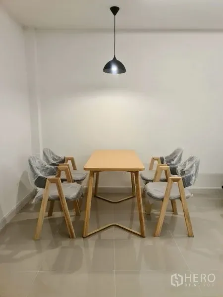 ทาวน์เฮาส์ ให้เช่าในKhlong Toei, Bangkok - มุมรับประทานอาหารมินิมอล โต๊ะไม้พร้อมเก้าอี้สี่ตัว ใต้โคมไฟแขวน พื้นกระเบื้อง