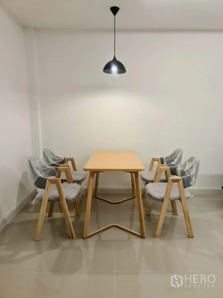 ทาวน์เฮาส์ ให้เช่าในKhlong Toei, Bangkok - มุมรับประทานอาหารมินิมอล โต๊ะไม้พร้อมเก้าอี้สี่ตัว ใต้โคมไฟแขวน พื้นกระเบื้อง
