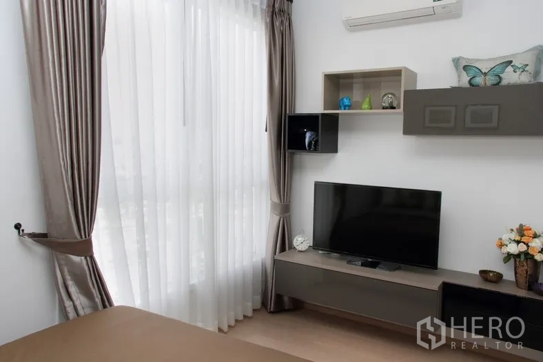 คอนโด ให้เช่าหรือขายในWatthana, Bangkok - มุมห้องนอนพร้อมชั้นวางทีวี ตู้แขวน และผ้าม่านสูงเต็มบาน