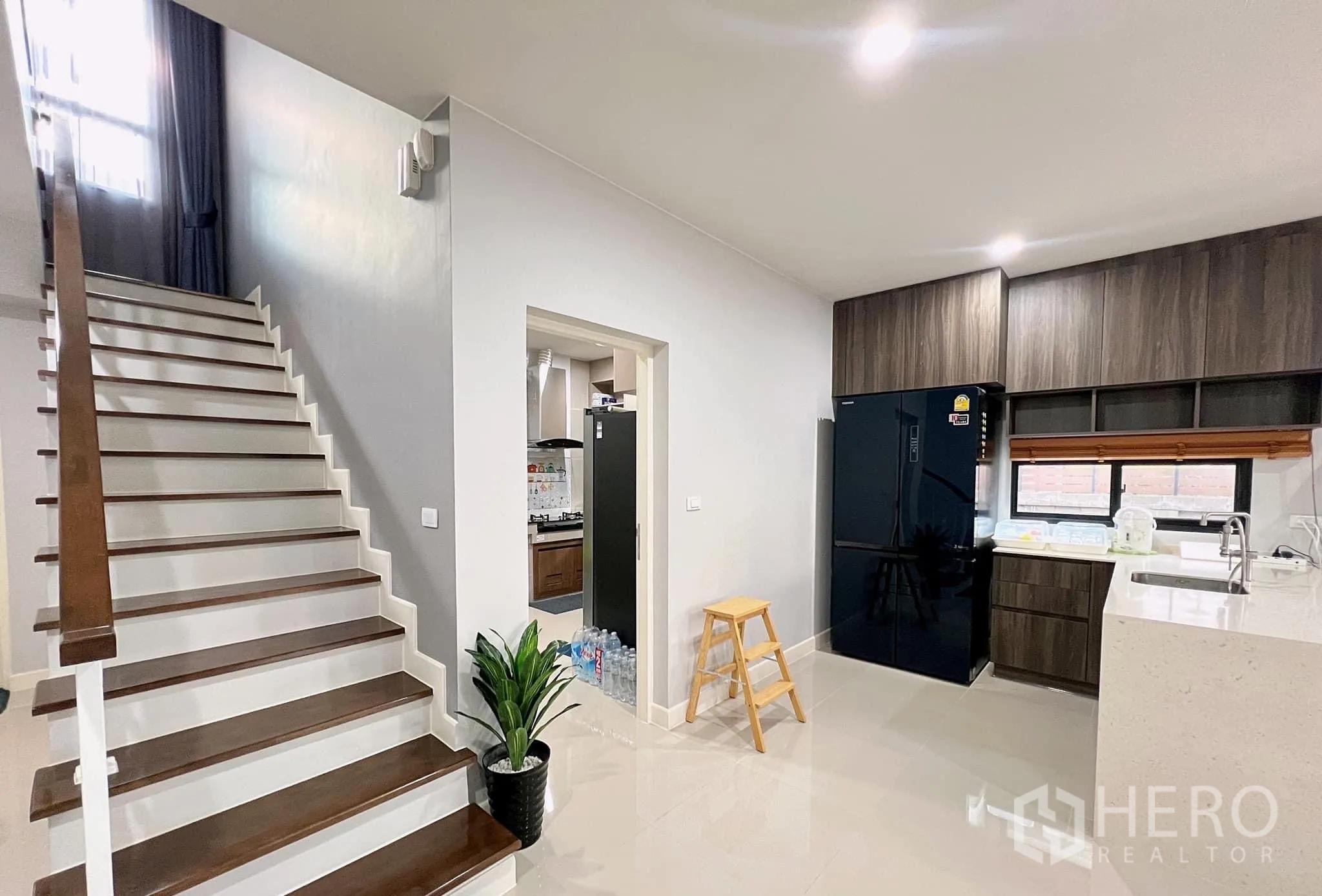 บ้าน ให้เช่าหรือขายในLam Luk Ka, Pathum Thani - บันไดชั้นล่างข้างครัวแบบเปิด ไอแลนด์ และตู้เย็นทรงสูง
