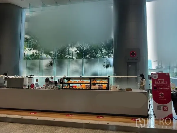 พื้นที่ขายปลีก ให้เช่าในBang Rak, Bangkok - คีออสค้าปลีกร่วมสมัย ตู้โชว์ไฟสว่าง ใต้เสากลมสูงและผนังกระจกฝ้าในล็อบบี้อาคารสำนักงาน