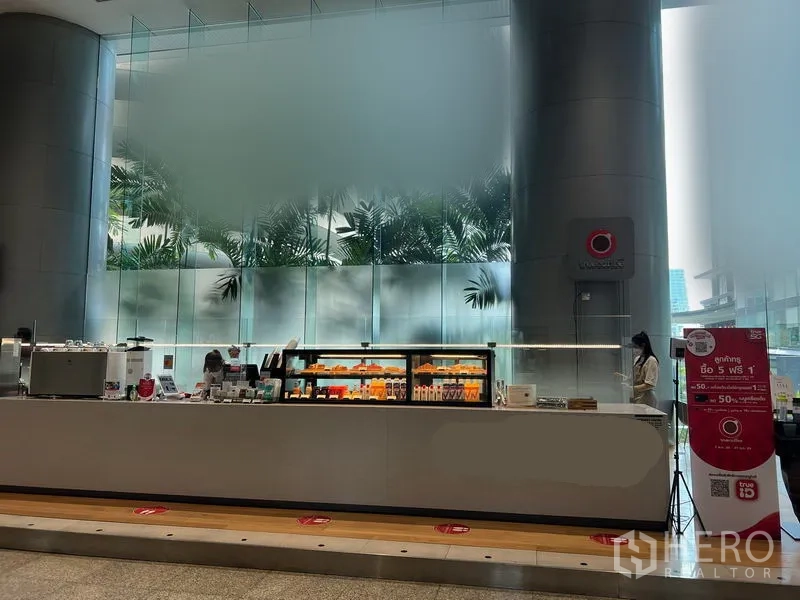 พื้นที่ขายปลีก ให้เช่าในBang Rak, Bangkok - คีออสค้าปลีกร่วมสมัย ตู้โชว์ไฟสว่าง ใต้เสากลมสูงและผนังกระจกฝ้าในล็อบบี้อาคารสำนักงาน