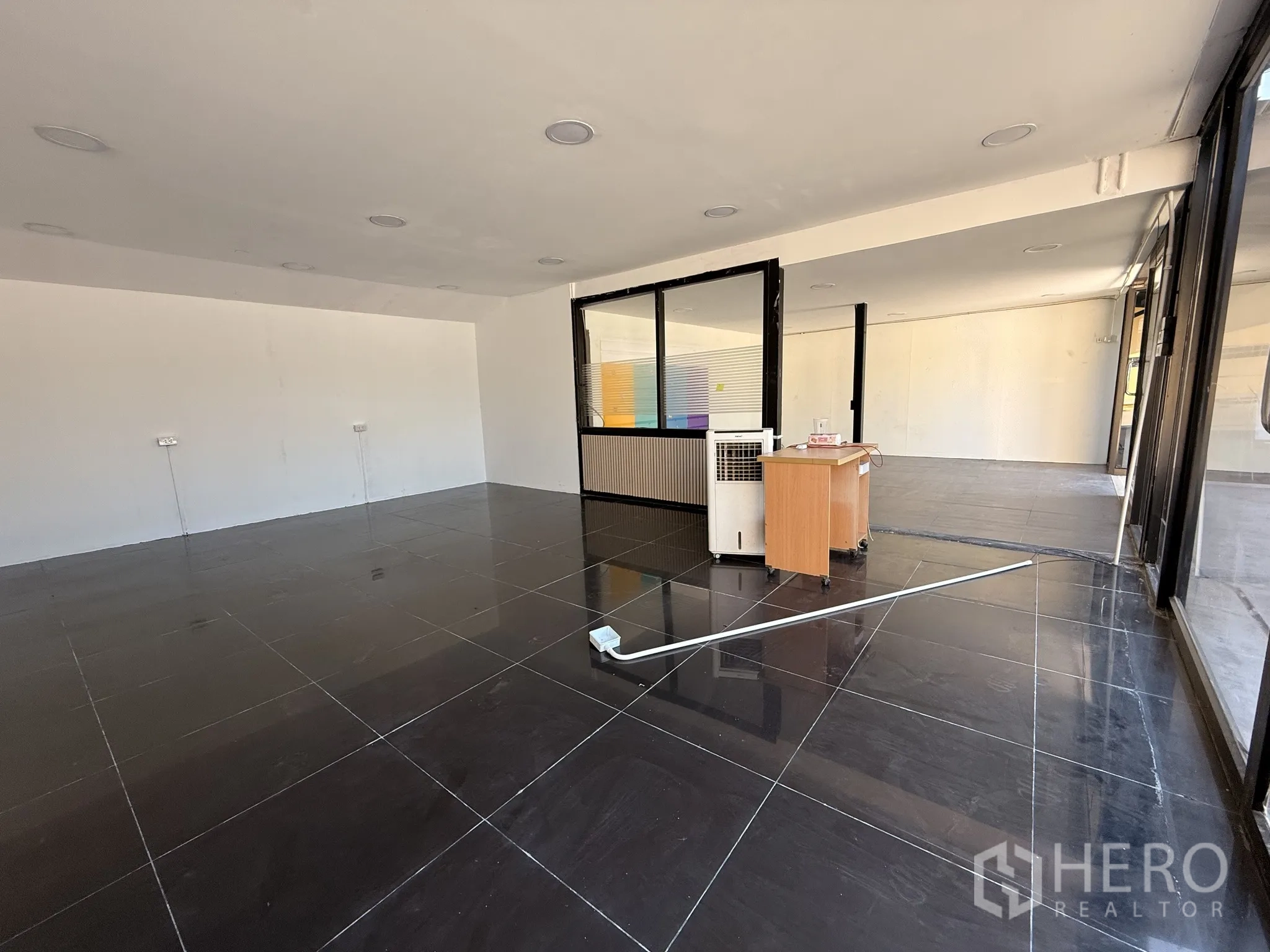 คลังสินค้า for rent in Lat Krabang, Bangkok - พื้นที่โชว์รูมหรือสำนักงานแบบเปิด พื้นกระเบื้องสีดำ ผนังกระจก และเคาน์เตอร์ต้อนรับ