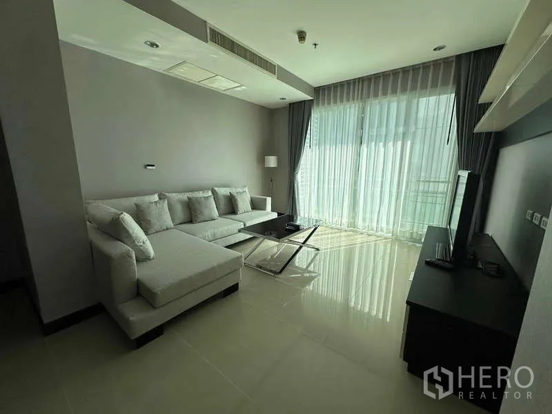 คอนโด ให้เช่าหรือขาย - ห้องนั่งเล่นสว่างที่ The Prime 11 พร้อมโซฟาเข้ามุม ชั้นวางทีวี และผ้าม่านโปร่งแบบเต็มผนัง