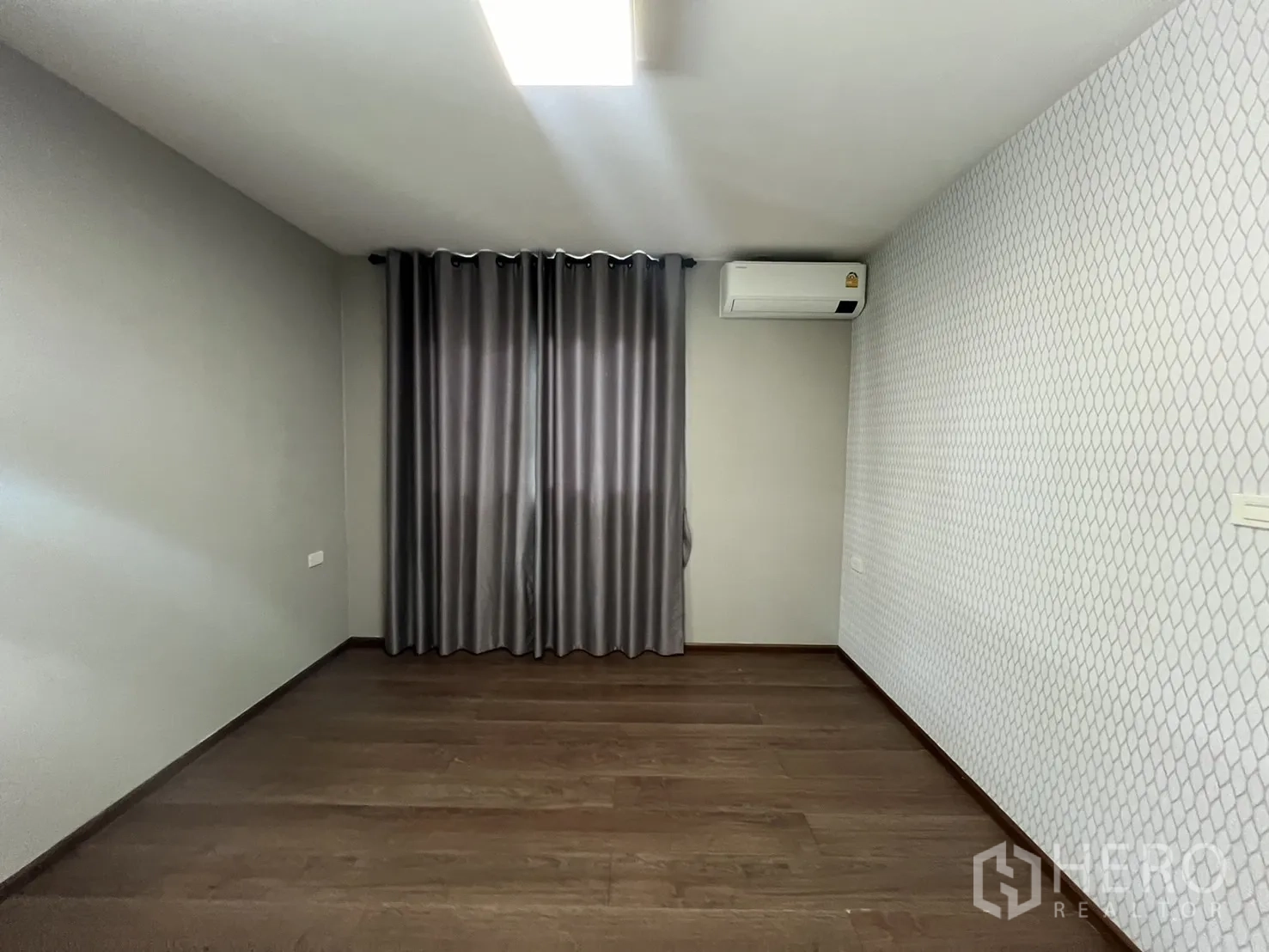Detached House for rent in Bang Phli, Samut Prakan - Empty bedroom with wood floor, gray curtains and a patterned accent wall.