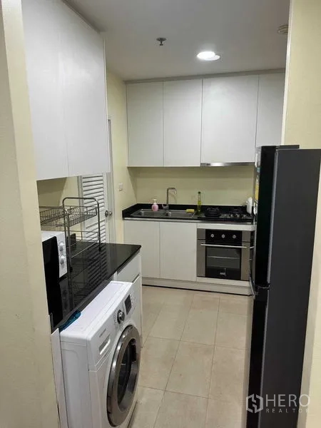 คอนโด ให้เช่าหรือขายในBangkok - ครัวแบบแกลลีย์ ตู้สีขาว ท็อปสีดำ มีเครื่องซักผ้าและเตาอบ