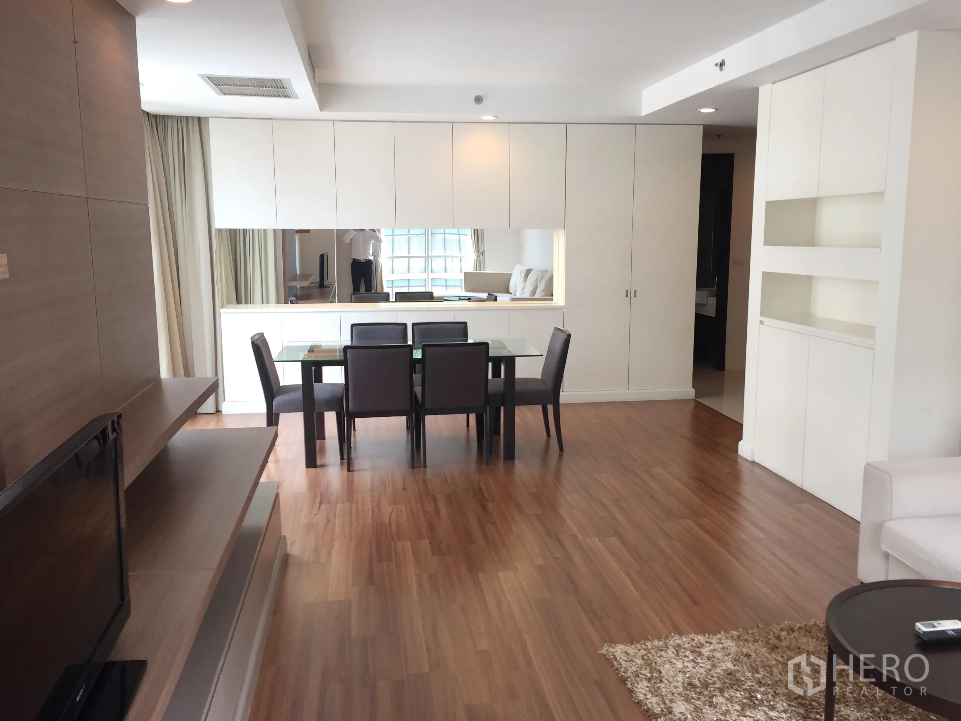 คอนโด ให้เช่าในPathum Wan, Bangkok - พื้นที่นั่งเล่นและรับประทานอาหารแบบโอเพ่น โปร่งสว่าง พื้นไม้ โต๊ะกระจก และตู้บิวท์อินสีขาวพร้อมกระจกบานยาว