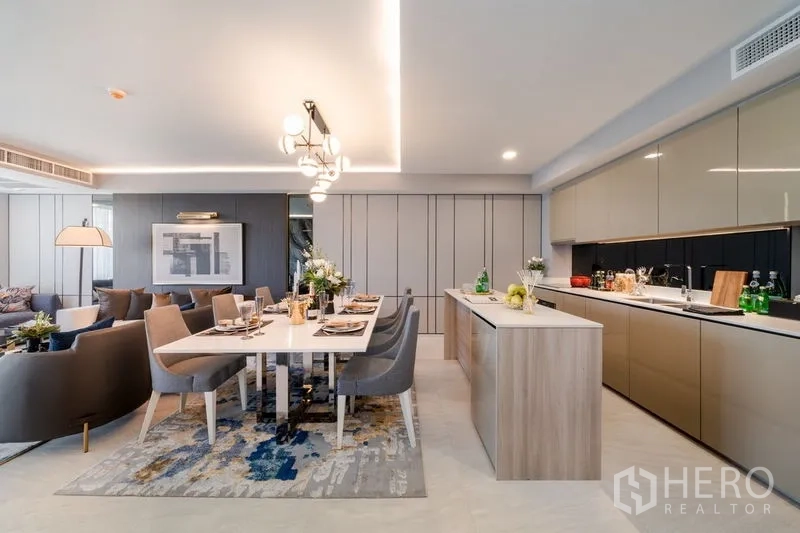 คอนโด ขายในWatthana, Bangkok - โซนรับแขก รับประทานอาหาร และครัวแบบเปิด มีไอส์แลนด์ยาว โต๊ะอาหารหกที่นั่ง ไฟดีไซน์ และตู้ครัวทันสมัย