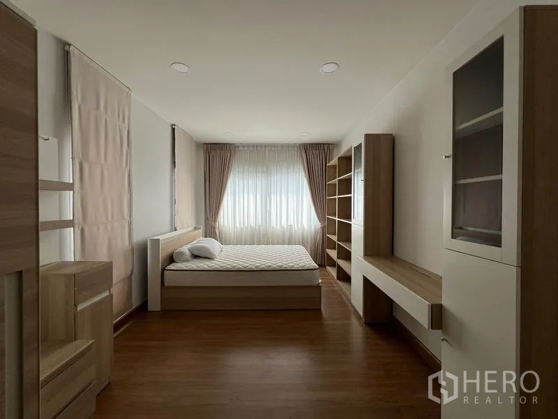 Detached House for rent in Bang Phli, Samut Prakan - Bedroom with wood built-ins, shelving and large window drapes.