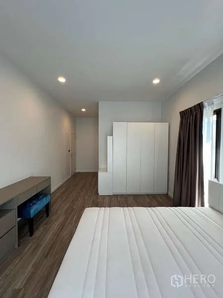 Detached House for rent in Bang Kapi, Bangkok - Large bedroom with bed, desk, freestanding wardrobe and wide window.