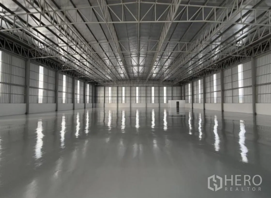 Warehouse for rent in Bang Khun Thian, Bangkok - Aerial view of the warehouse facade and fenced concrete yard.