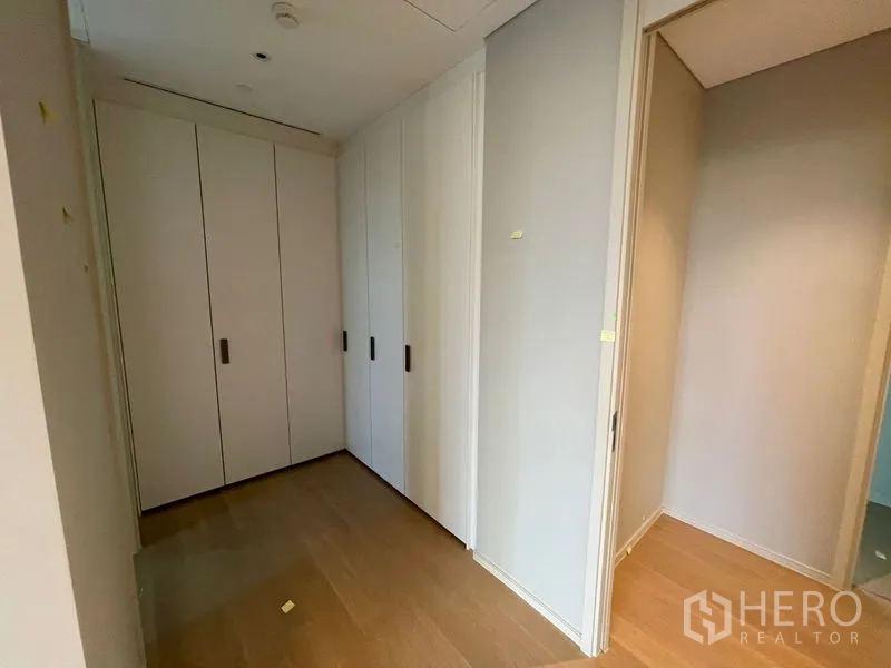 Condominium for rent or sale in Pathum Wan, Bangkok - Hallway with built-in white wardrobes and wood flooring in a modern Bangkok condo.