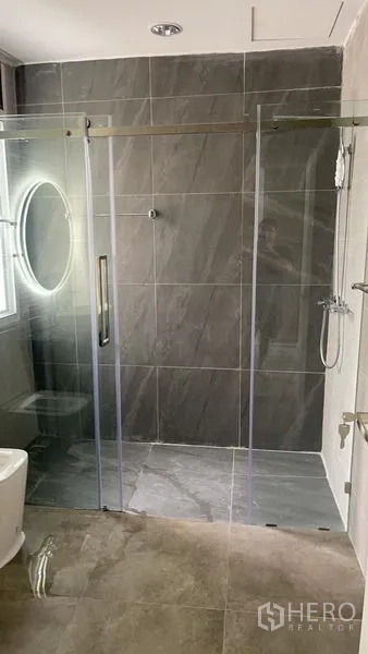 Townhouse for sale in Din Daeng, Bangkok - Contemporary bathroom with glass-enclosed shower, handheld shower set and grey wall tiles.