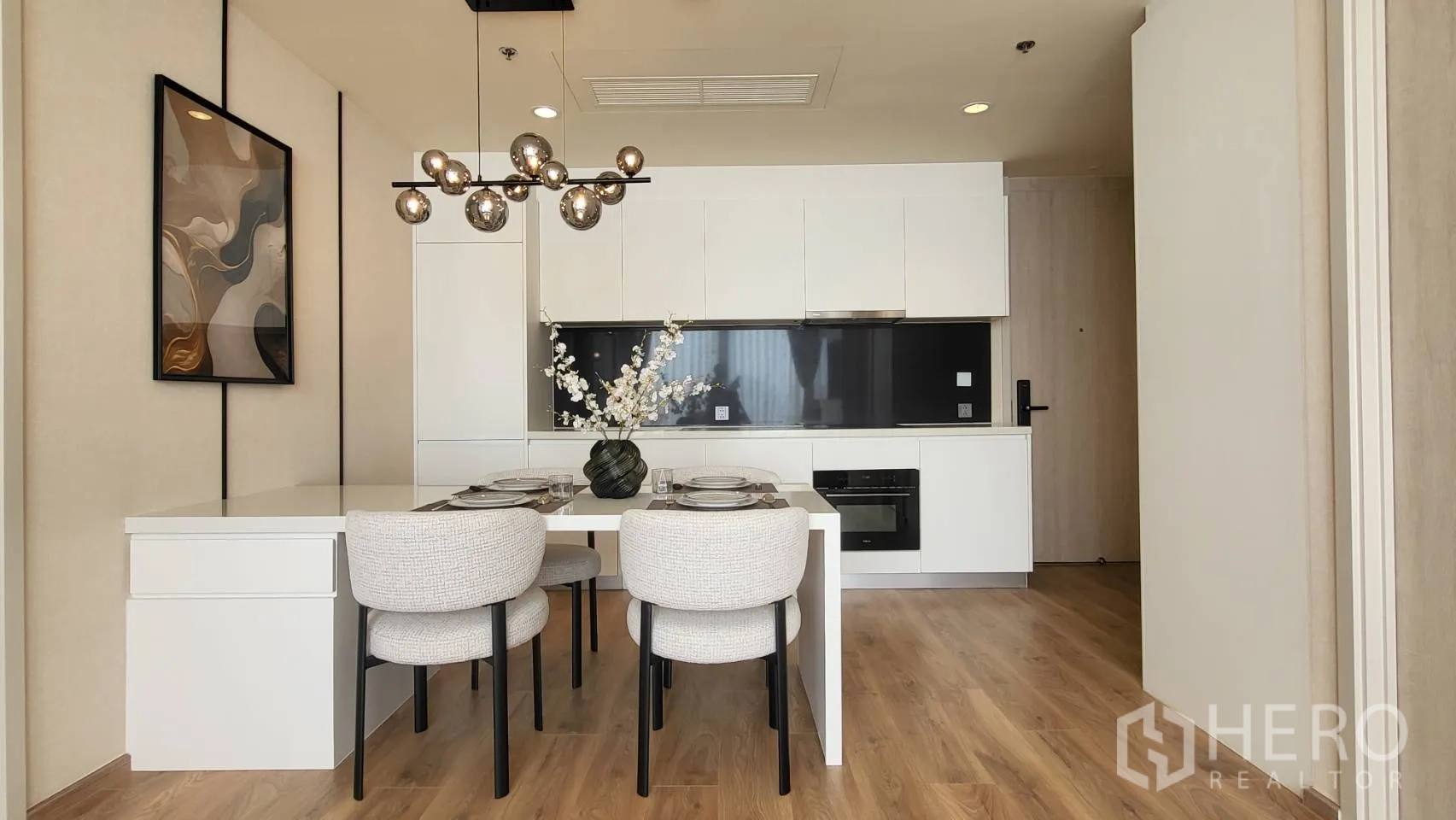 公寓 for sale in Watthana, Bangkok - 白色一体化厨房，橱柜、嵌入式烤箱、黑色挡板与四人岛台。