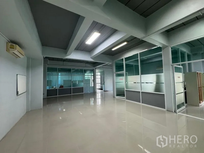 Warehouse for rent or sale in Chon Buri - Wide office hall with polished floors and framed glass rooms.