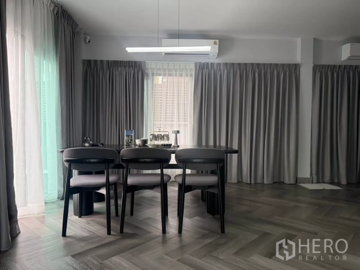 Detached House for rent in Bang Phli, Samut Prakan - Dining area with four-seat table, large windows and grey drapes on herringbone flooring.