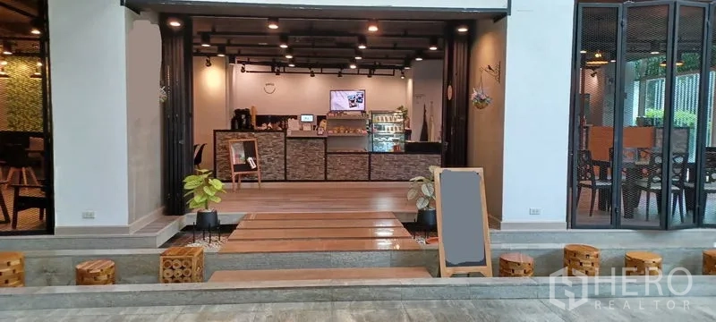 零售空间 出租在Khlong Toei, Bangkok - 室内零售区，服务吧台、展示冷柜、木质台阶与方形坐凳。