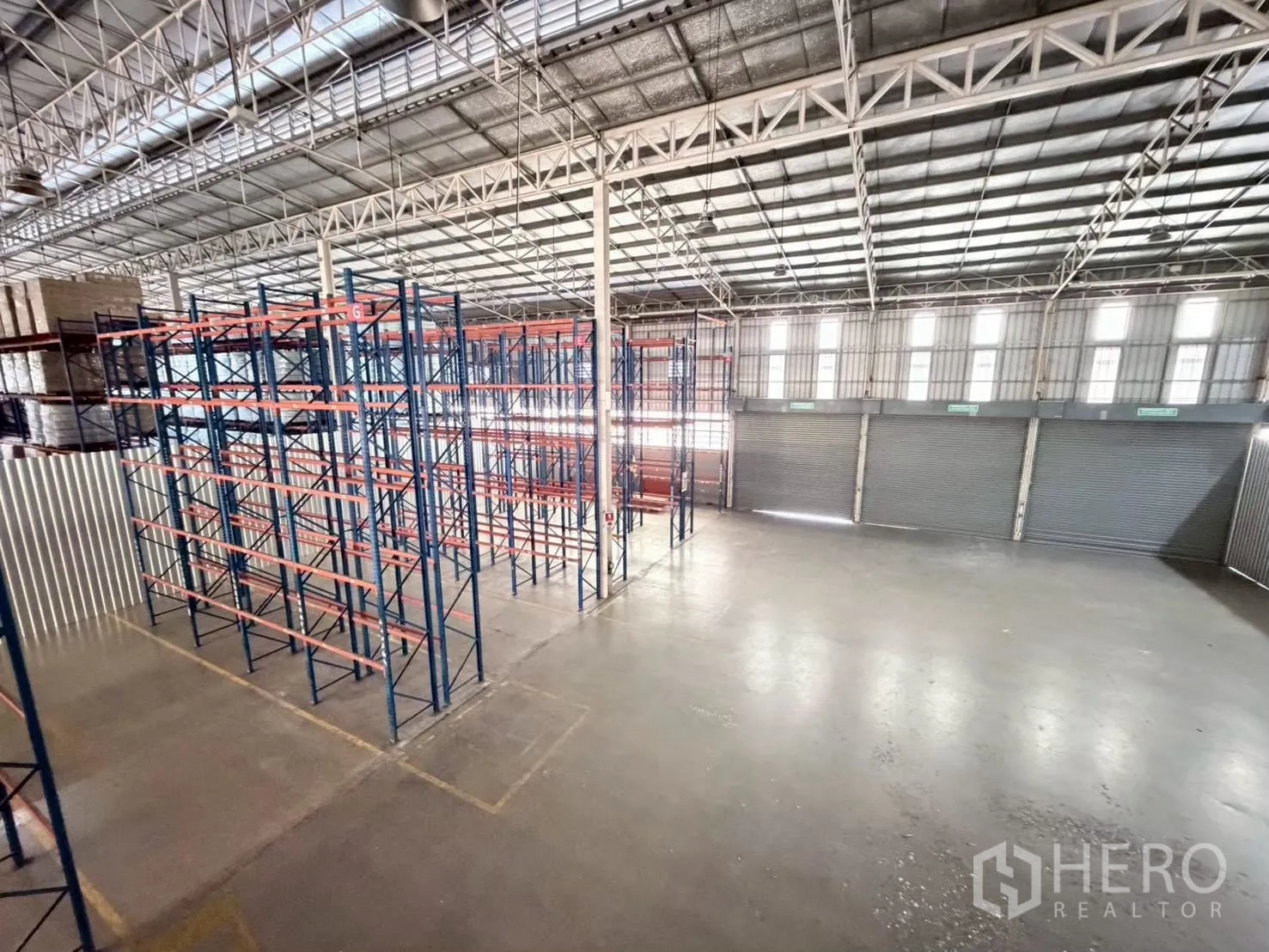 Warehouse for rent in Bang Sue, Bangkok - Warehouse bay with pallet racking, polished floor, and multiple roller shutter doors.