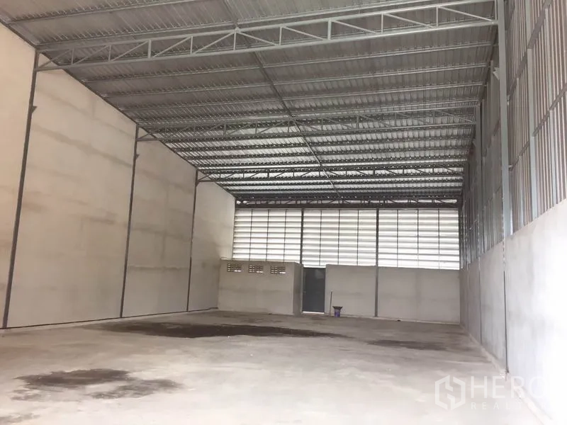 Warehouse for rent in Sai Noi, Nonthaburi - Spacious warehouse interior with high steel truss roof, concrete floor, and ventilated panels.
