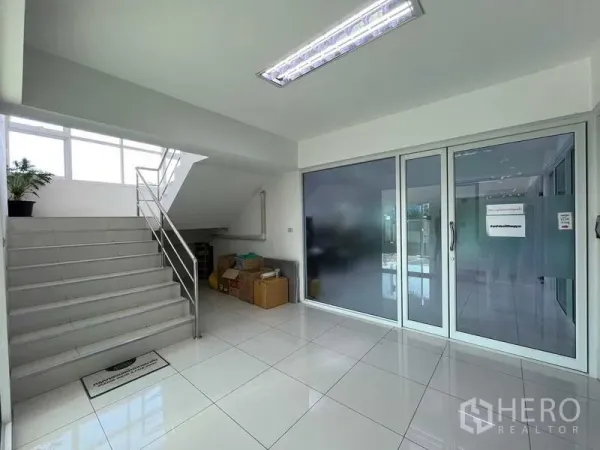 คลังสินค้า ให้เช่าหรือขายในNonthaburi - โถงต้อนรับสว่างพื้นกระเบื้องสีขาว บันได และประตูกระจกเข้าสู่พื้นที่สำนักงาน