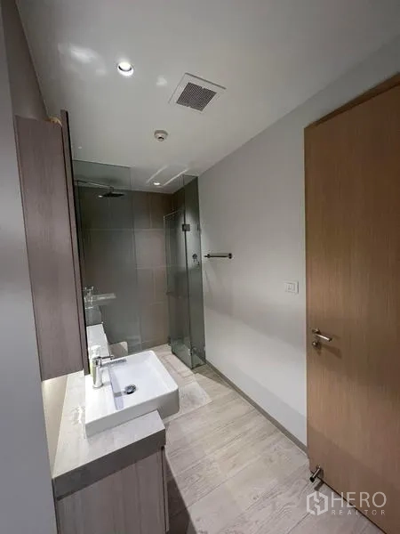 公寓 出租 - 现代浴室，玻璃淋浴间与单盆洗手台。