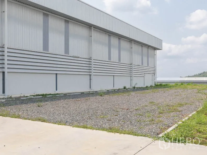 工厂 出租在Si Racha, Chon Buri - 厂房侧院的碎石空地与绿化带