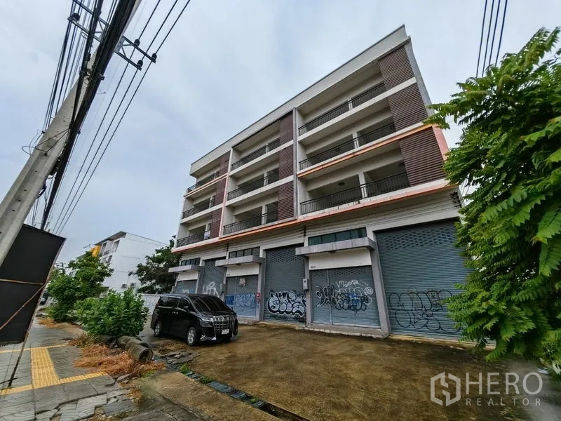 Home Office for rent or sale in Lam Luk Ka, Pathum Thani - Modern multi-storey home office block with ground-floor roller shutters and parking area in Lam Luk Ka.