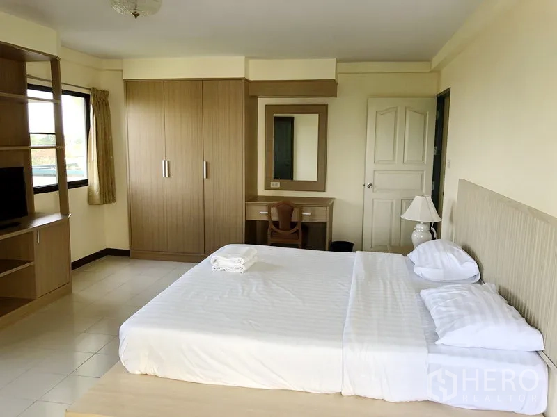 Apartment for rent in Suan Luang, Bangkok - Master bedroom with wardrobe, vanity nook and king bed in neutral décor.