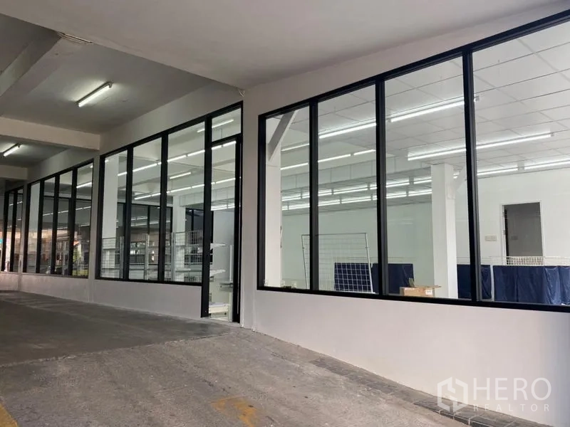 Office Space for rent in Chatuchak, Bangkok - Glass facade of the office along a covered parking lane with lighting.
