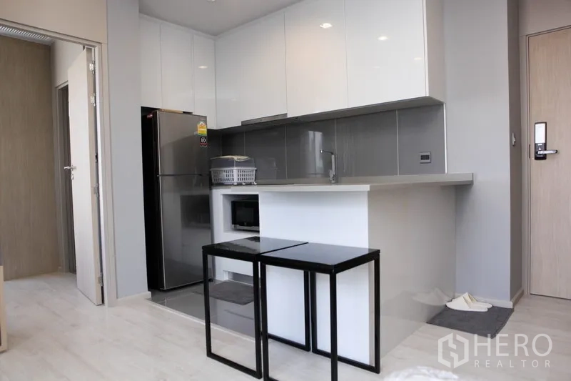 公寓 出租在Watthana, Bangkok - 白色一字形厨房，亮面柜体、大冰箱与半岛台面